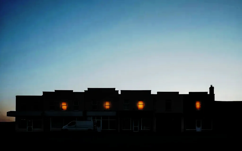 A row of small main-street commercial buildings in silhouette at dusk